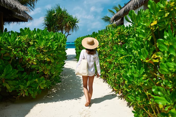 Woman walking on path to beach