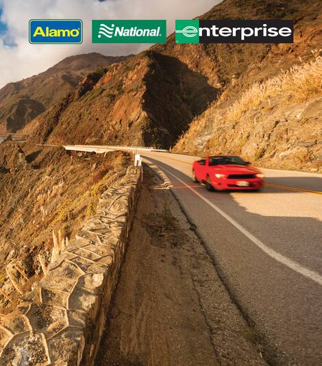 A red sports car set against cliffs and the ocean. Three car rental company logos; "Alamo", "National", and "Enterprise" are featured at the top of the image. 