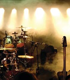 A smoky and darkly lit stage of a band's instruments.