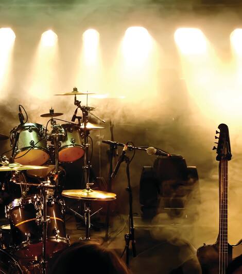 A smoky and darkly lit stage of a band's instruments.