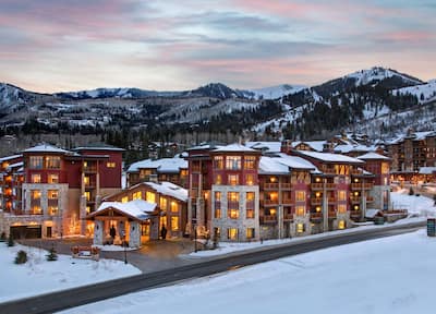 A snow-capped hotel at dusk with mountains in the background