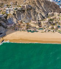 a bird's eye view of a hotel resort built into a cliff on a beach