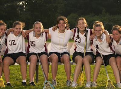 A girls' lacrosse team posing for a picture with their coach.
