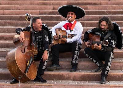 Members of mariachi band sitting on steps and laughing