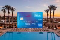 AmEx credit card in foreground with pool and palm trees in background