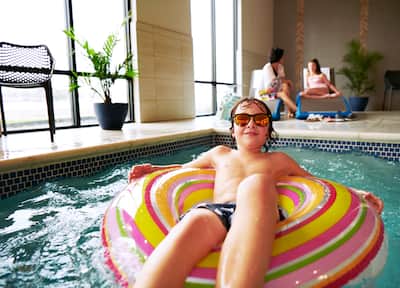 Young boy in sunglasses on a float inside indoor pool