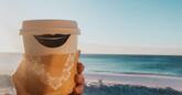 A Hampton coffee cup in foreground of picture of beach
