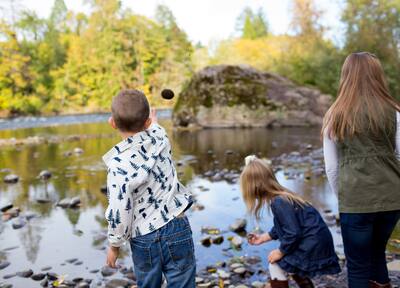 Three kids who are siblings in a candid lifestyle photo outdoors along the banks of the McKenzie River in Oregon.