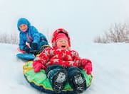 Kids tubing down in hill in the winter snow