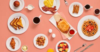 A selection of breakfast dishes set against a coral-colored background