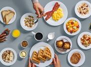A selection of breakfast dishes set against a gray background
