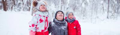 Three children bundled up amid snow drifts