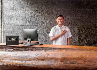 Man with hand over heart standing behind hotel front desk