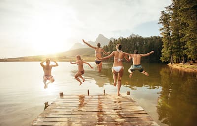 Group of friends jumping in lake