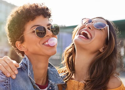 Two female friends laughing with sunglasses on