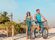 Couple biking on Florida beach with lighthouse in the background