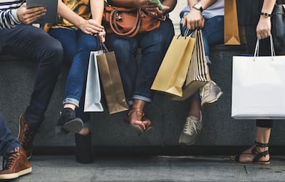 people sitting while holding shopping bags