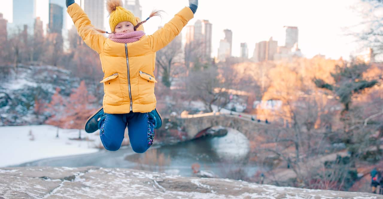Girl in yellow jacket jumping in Central Park, New York City