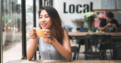 Young Asian woman drinking coffee at a cafe.