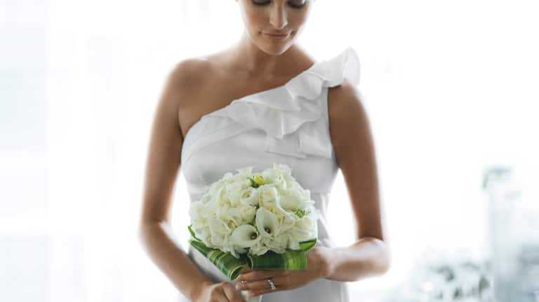Mariage Brunette aux yeux fermés tenant un bouquet de fleurs blanches