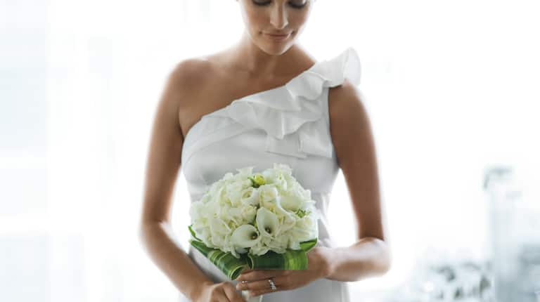 Brunette Bride With Closed Eyes Holding Bouquet of White Flowers 