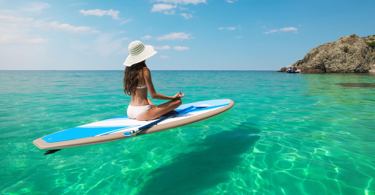 Young woman meditating in a sea on a paddle board in Hawaii.