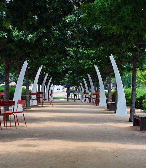 Live oak trees shade seating in summer along a walking path at Klyde Warren Park in downtown Dallas.