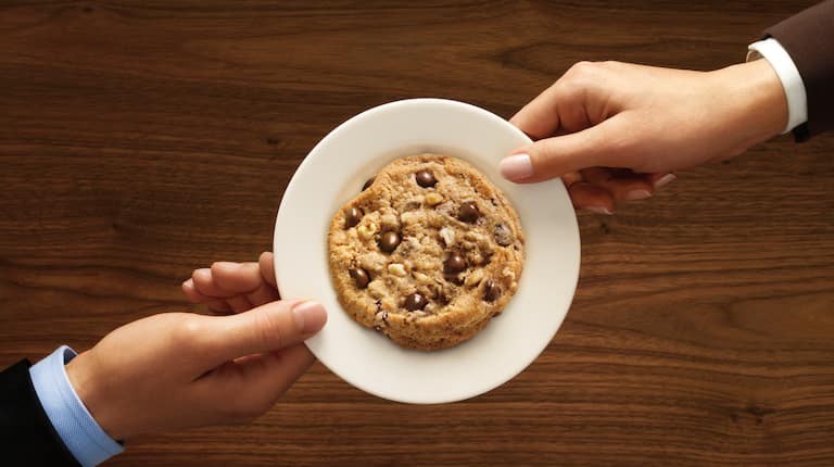 Vue de haut de deux mains tenant une assiette blanche avec un cookie