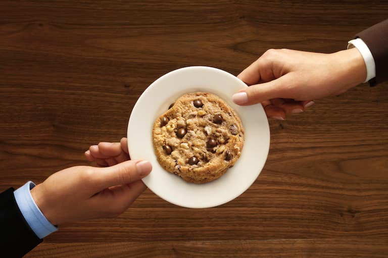 Vue de haut de deux mains tenant une assiette blanche avec un cookie