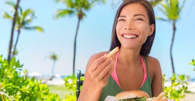 Woman eating french fries food at resort restaurant in Florida.