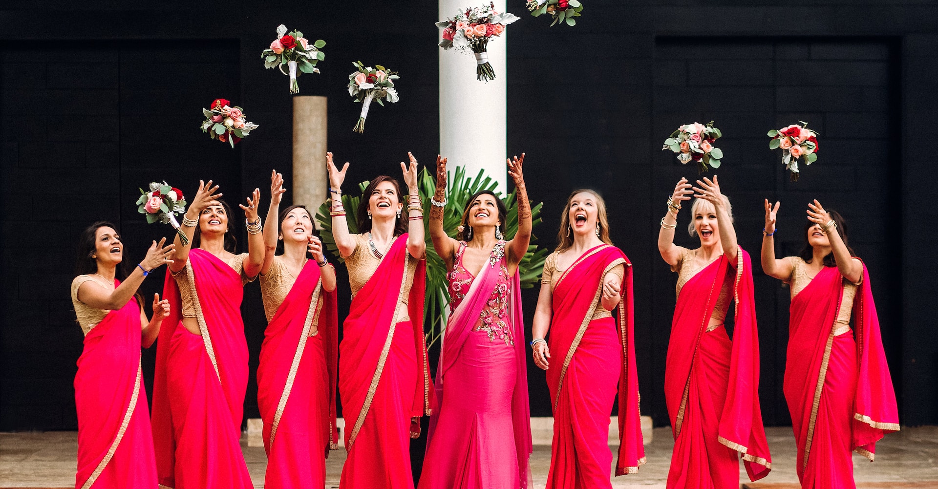 Indian bride and bridesmaids through their bouquets up before a wedding ceremony