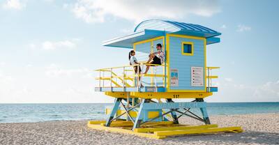 couple by lifeguard hut during sunrise at Miami Beach, Florida