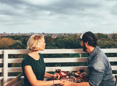 a couple celebrating with wine and food on a private terrace above the city of Amsterdam