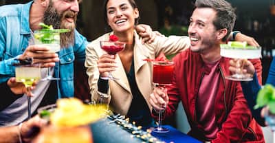 Hipster friends toasting multicolored fancy drinks at fashion bar 
