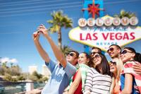 group of happy friends taking selfie by cell phone over welcome to fabulous las vegas sign background