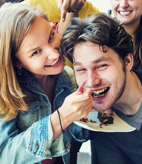 Couple smiling and eating dessert. 