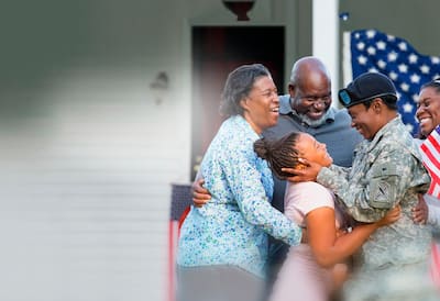 Military family hugging on front porch.