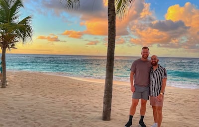 Two men next to palm tree in front of sunset