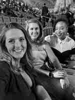 Tiga wanita bergaun formal tersenyum ke kamera