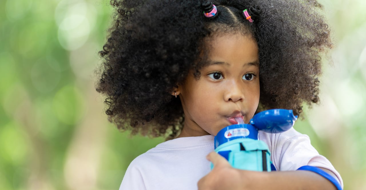 Children holding water plastic bottles and looking before a drink at outdoor.