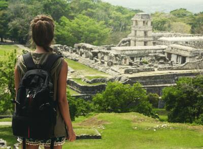 Hiker woman with backpack looking at ancient Mayan ruins