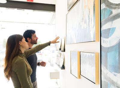 Woman and man are deciding which art painting to buy for their home from the exhibition.