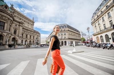 Young stylish woman in red pants crossing the street in Paris