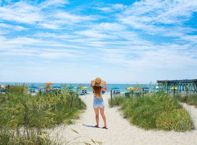 Girl waking on the beach. Footpath on sand dunes and ocean in the background. Myrtle Beach, South Carolina, USA