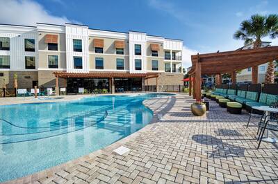 A Home2 Suites outdoor pool area and patio with seating