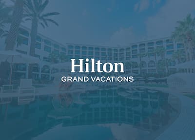 A hotel pool and exterior with the Hilton Grand Vacations logo layered over the top