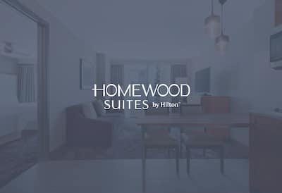 A suite with the Homewood Suites by Hilton logo layered over the image