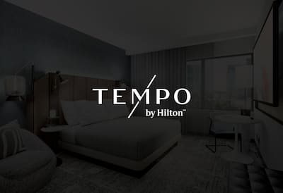 A hotel bedroom with the Tempo logo featured over the top of the image