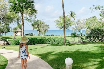 Güneş şapkalı kız palmiye ağaçlarının yanında yürüyor