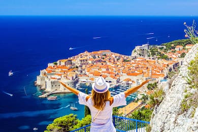 Woman in white attire viewing Ragusa town on Dalmatian Coast